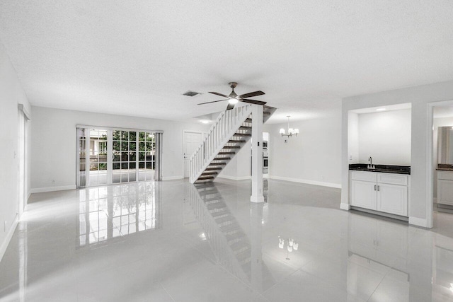 1701 Vision Dr, Palm Beach Gardens, FL 33418 - unfurnished living room featuring a ceiling fan, baseboards, stairway, a chandelier, and a textured ceiling