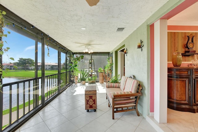 sunroom featuring ceiling fan and a water view