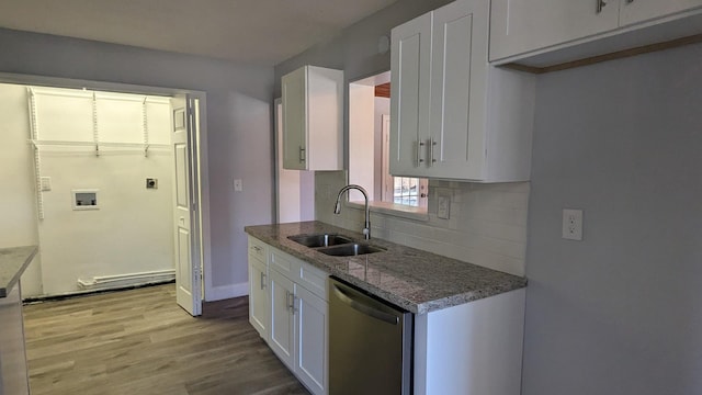 kitchen with white cabinets, stainless steel dishwasher, sink, and light hardwood / wood-style flooring