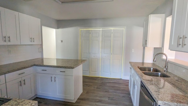 kitchen with light stone counters, stainless steel dishwasher, sink, dark hardwood / wood-style floors, and white cabinetry