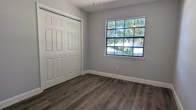 unfurnished bedroom with a closet and dark hardwood / wood-style floors