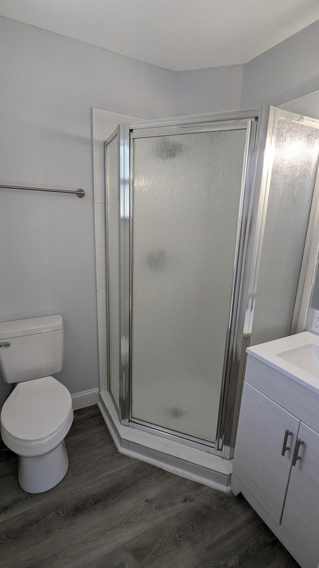 bathroom with vanity, hardwood / wood-style flooring, toilet, and a shower with door