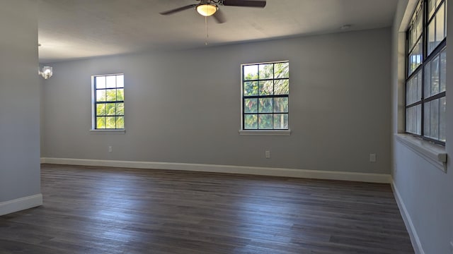 unfurnished room featuring ceiling fan with notable chandelier, dark hardwood / wood-style flooring, and a healthy amount of sunlight