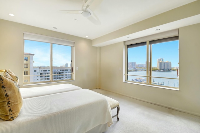 bedroom with carpet floors, ceiling fan, and a water view