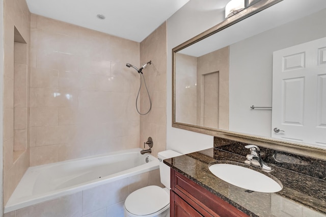 full bathroom with tiled shower / bath, vanity, and toilet