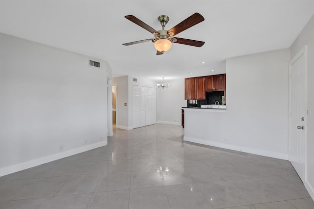 unfurnished living room featuring light tile patterned flooring and ceiling fan with notable chandelier