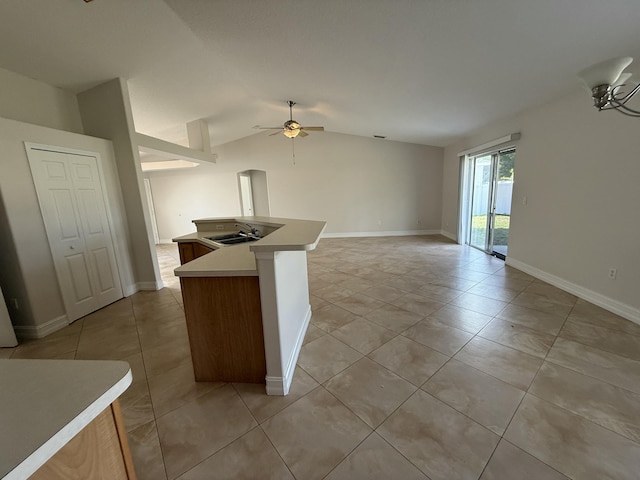 kitchen featuring sink, vaulted ceiling, light tile patterned floors, ceiling fan, and a kitchen island with sink