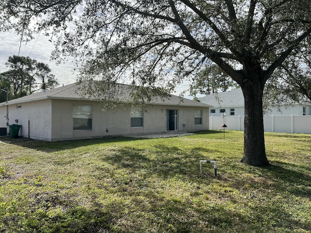 rear view of property with a yard and central air condition unit