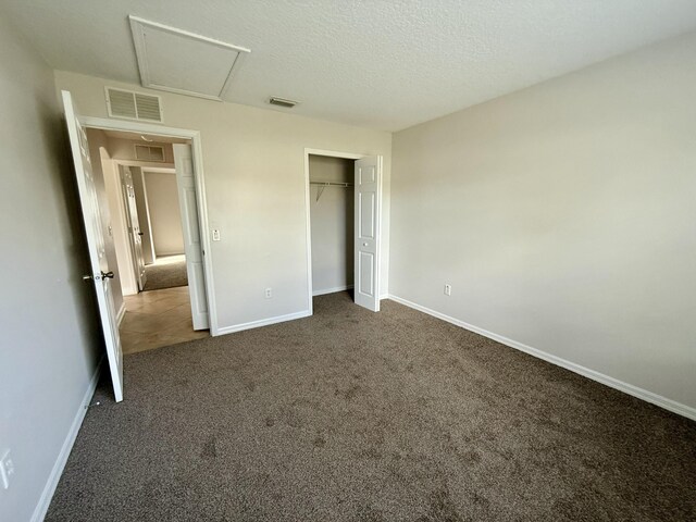 unfurnished bedroom featuring dark colored carpet, a textured ceiling, and a closet