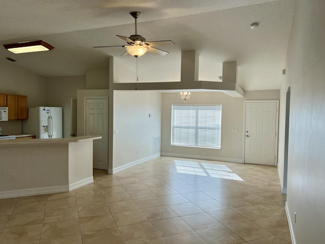 kitchen with light tile patterned flooring, ceiling fan with notable chandelier, high vaulted ceiling, white appliances, and a textured ceiling