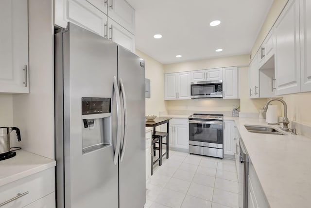 kitchen with white cabinetry, sink, light tile patterned floors, and appliances with stainless steel finishes