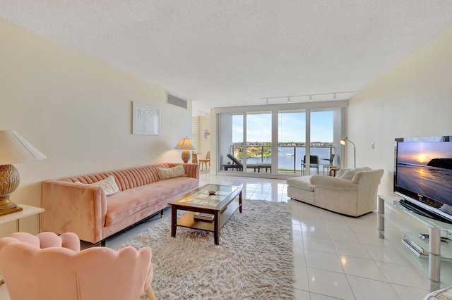 living room featuring rail lighting, light tile patterned floors, and a textured ceiling