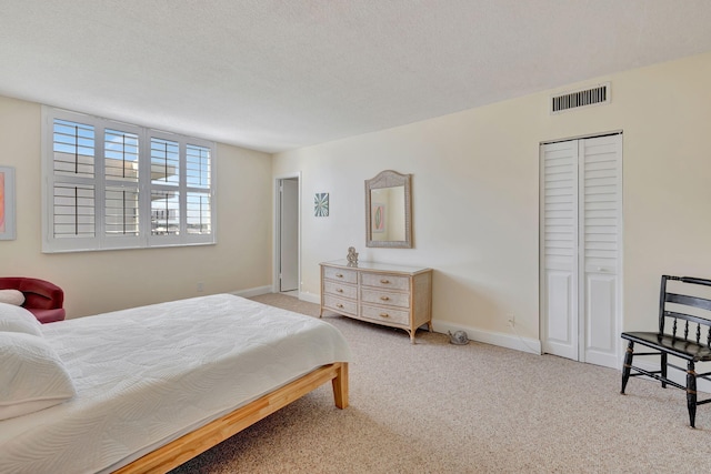 carpeted bedroom featuring a textured ceiling and a closet