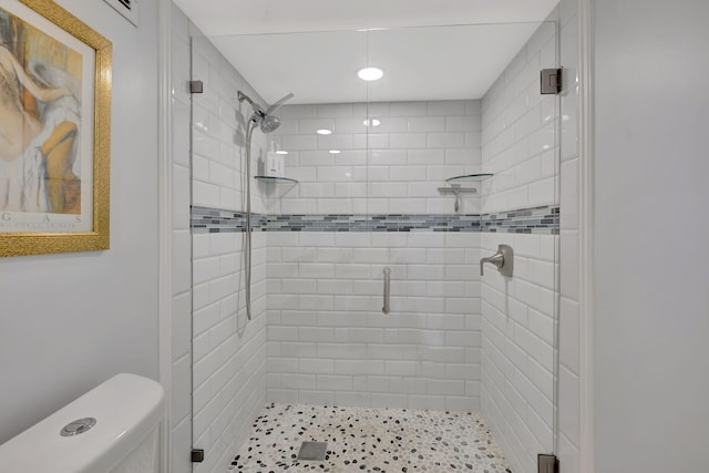 bathroom featuring toilet and a shower with shower door