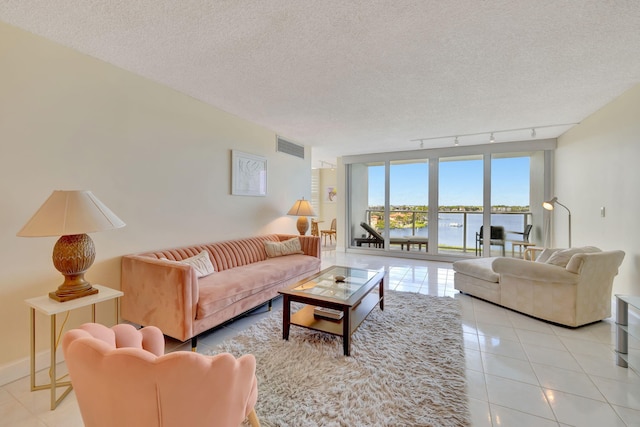 living room with light tile patterned floors, a textured ceiling, a water view, and rail lighting