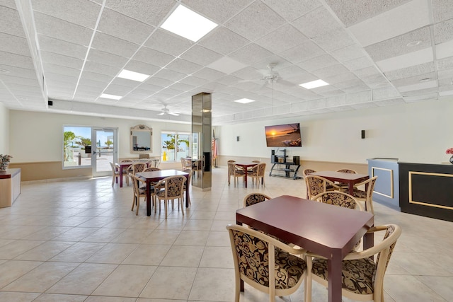 tiled dining area featuring ceiling fan and a drop ceiling