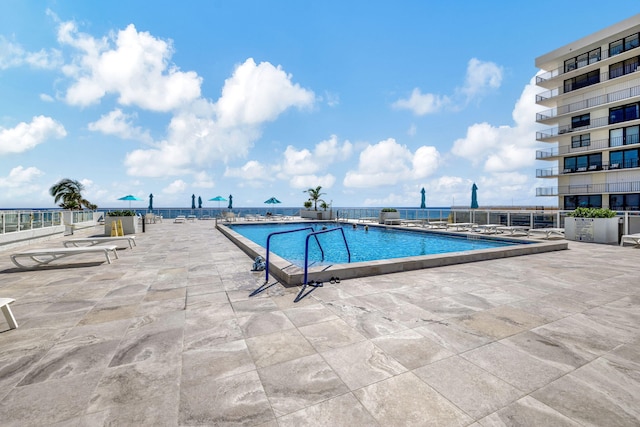 view of swimming pool with a water view and a patio