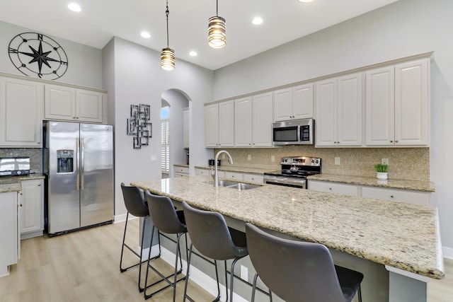 kitchen with sink, decorative light fixtures, a center island with sink, white cabinets, and appliances with stainless steel finishes