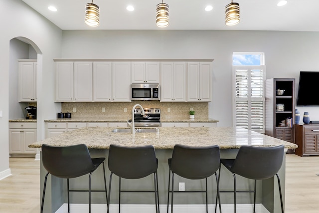 kitchen featuring light stone countertops, white cabinetry, sink, and appliances with stainless steel finishes