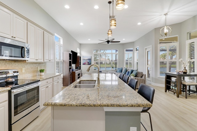 kitchen featuring sink, stainless steel appliances, tasteful backsplash, decorative light fixtures, and a kitchen bar