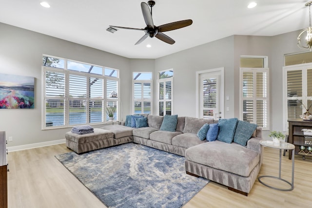 living room with ceiling fan with notable chandelier and wood-type flooring