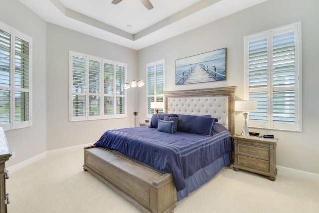 bedroom featuring a tray ceiling, ceiling fan, and light carpet