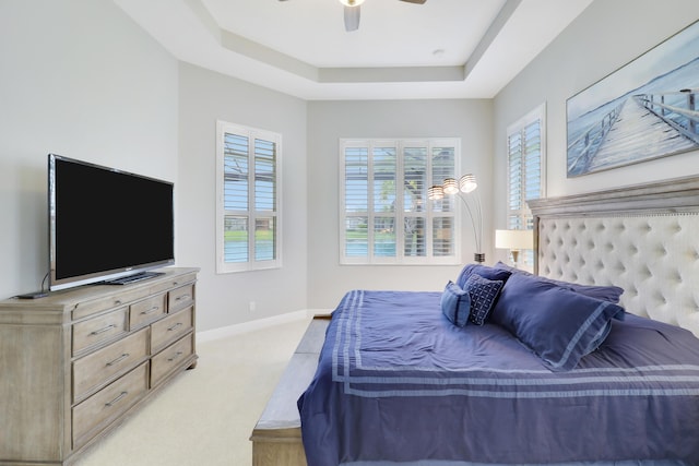 carpeted bedroom featuring a tray ceiling and ceiling fan