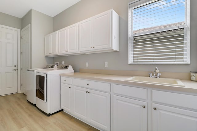 washroom featuring cabinets, independent washer and dryer, sink, and light hardwood / wood-style flooring