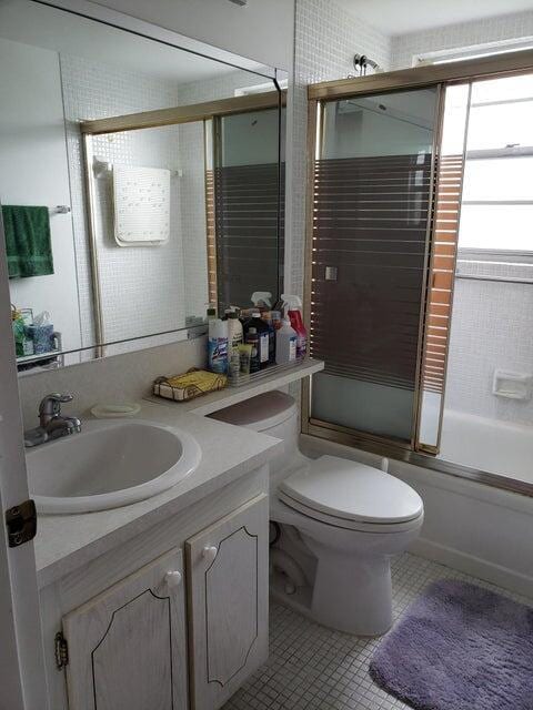 full bathroom featuring tile patterned flooring, vanity, enclosed tub / shower combo, and toilet