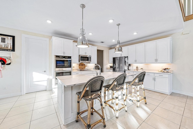 kitchen featuring white cabinets, an island with sink, decorative light fixtures, and appliances with stainless steel finishes