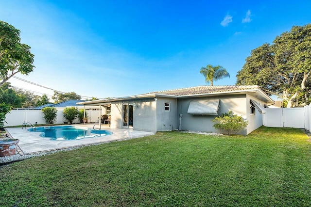 back of house featuring a lawn, a patio area, and a fenced in pool