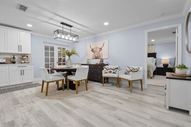 dining room with light hardwood / wood-style flooring, ornamental molding, french doors, and a textured ceiling