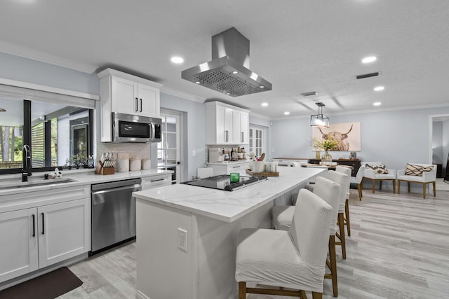 kitchen featuring island range hood, a kitchen island, white cabinets, and appliances with stainless steel finishes