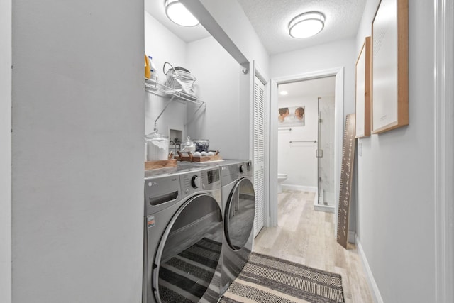 laundry area with light hardwood / wood-style floors, washer and dryer, and a textured ceiling