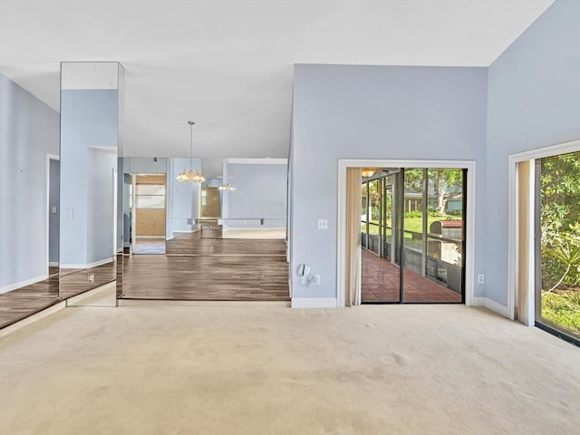 unfurnished living room with a chandelier, carpet flooring, and a healthy amount of sunlight