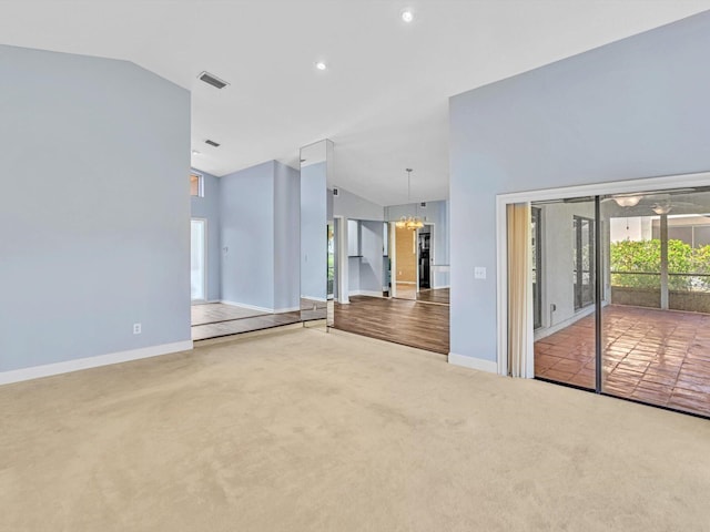 unfurnished living room featuring carpet flooring, an inviting chandelier, and vaulted ceiling