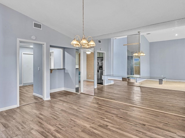 unfurnished dining area featuring a textured ceiling, wood-type flooring, vaulted ceiling, and a notable chandelier