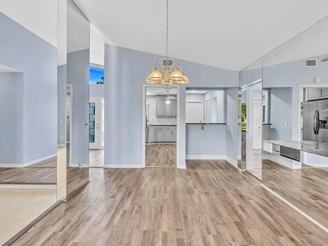 unfurnished living room featuring hardwood / wood-style flooring, high vaulted ceiling, and a notable chandelier