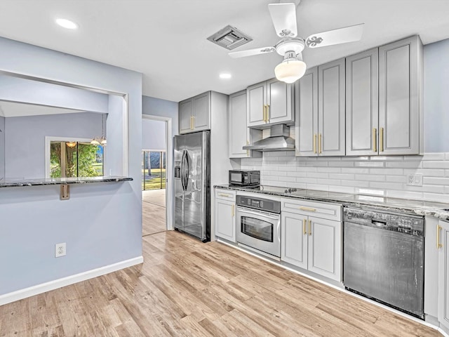 kitchen featuring tasteful backsplash, gray cabinetry, black appliances, stone countertops, and range hood