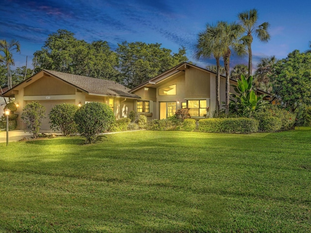 view of front of home with a garage and a lawn