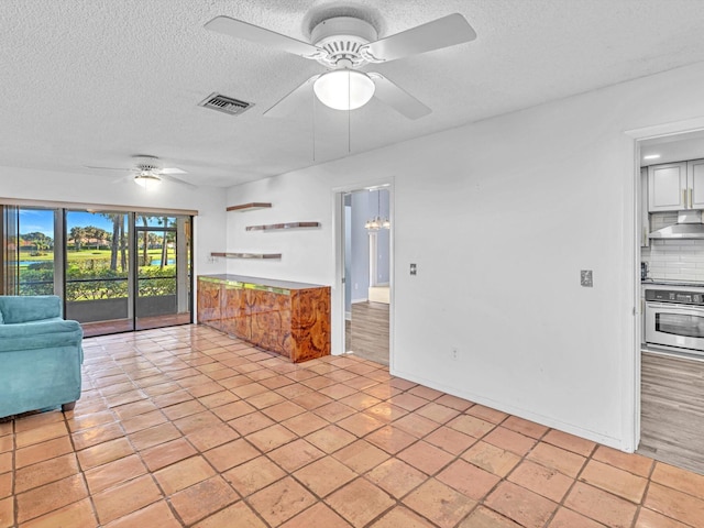 interior space featuring ceiling fan, light tile patterned flooring, and a textured ceiling