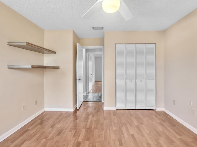 unfurnished bedroom featuring ceiling fan, a closet, a textured ceiling, and light wood-type flooring