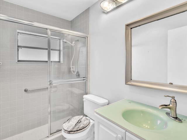 bathroom featuring a shower with door, vanity, and toilet