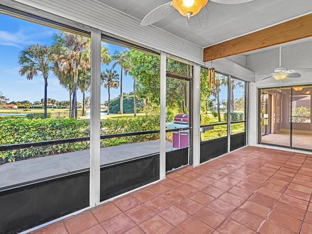 unfurnished sunroom featuring ceiling fan and beamed ceiling