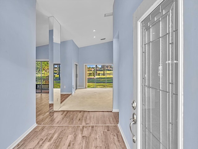 foyer entrance featuring high vaulted ceiling and light hardwood / wood-style flooring