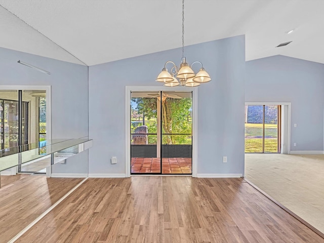 unfurnished dining area with lofted ceiling, hardwood / wood-style flooring, and a notable chandelier