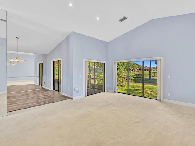 spare room with carpet, high vaulted ceiling, and a notable chandelier