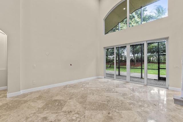 unfurnished living room featuring a towering ceiling