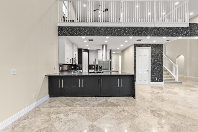 kitchen with sink, kitchen peninsula, a high ceiling, and white cabinets