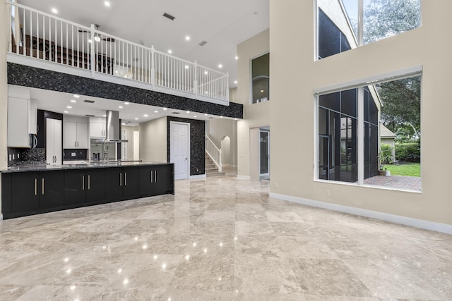 unfurnished living room with a high ceiling, a healthy amount of sunlight, and sink